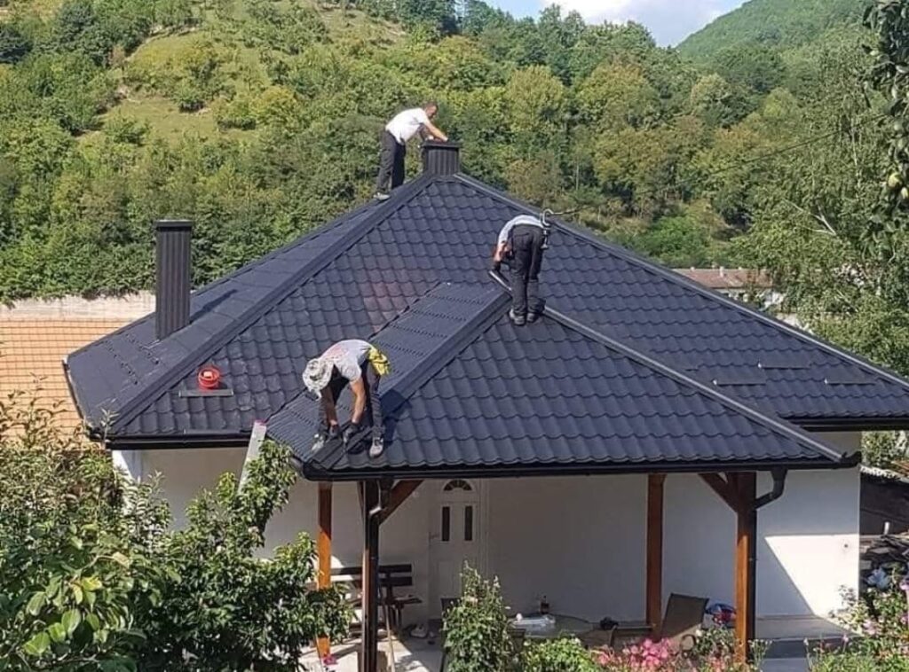 Echipă Vreau Acoperiș montând țiglă metalică pe un acoperiș în patru ape